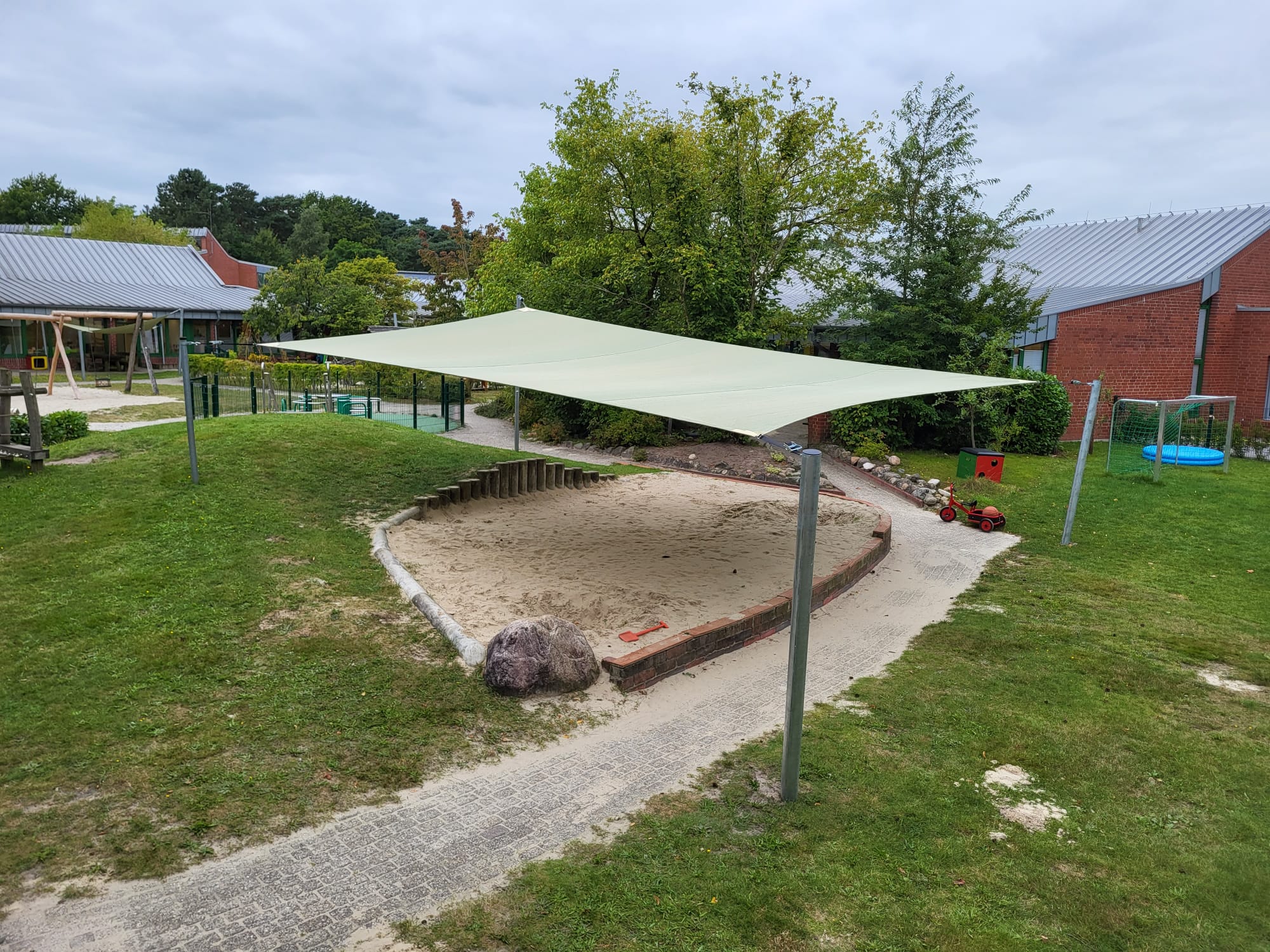 Sonnensegel über einem Sandkasten auf einem Spielplatz.